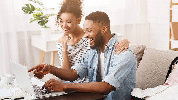 Happy couple searching sightseeings for trip on laptop