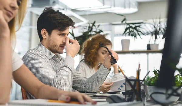 Molesto hombre milenario masajeando su puente nasal — Foto de Stock