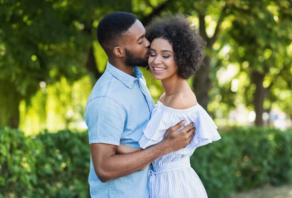 Afro-mężczyzna całuje swoją dziewczynę podczas chodzenia — Zdjęcie stockowe