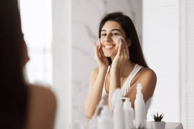 Beautiful girl remove makeup in front of mirror clipart