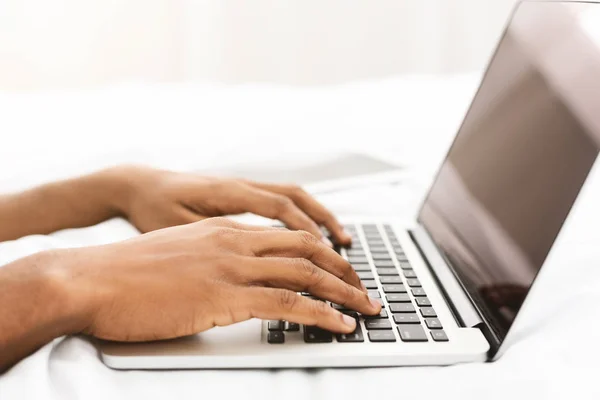 Black man blogger typing on laptop in bed — Stock Photo, Image