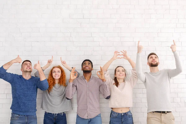 Diversos amigos haciendo gestos con las manos sobre la pared blanca — Foto de Stock