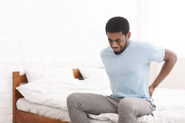 Hombre que sufre de dolor de espalda en casa en el dormitorio . —  Fotos de Stock