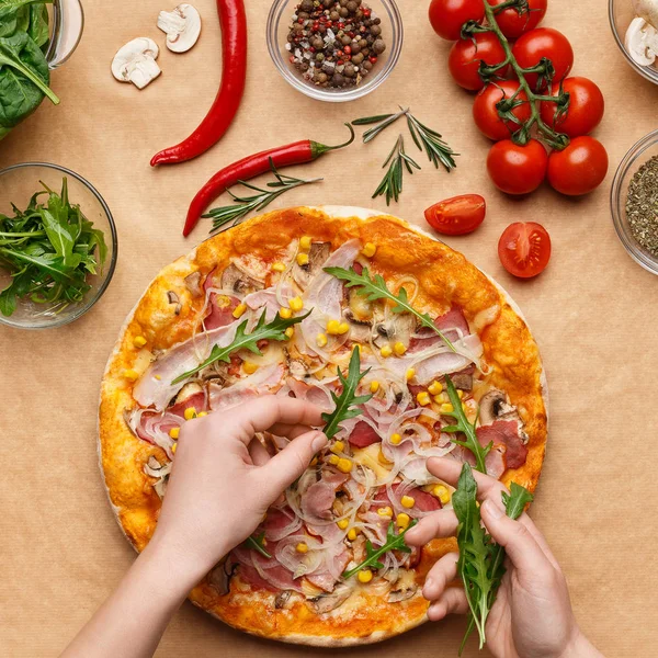 Koch ergänzt Pizza mit Rucola, Draufsicht — Stockfoto
