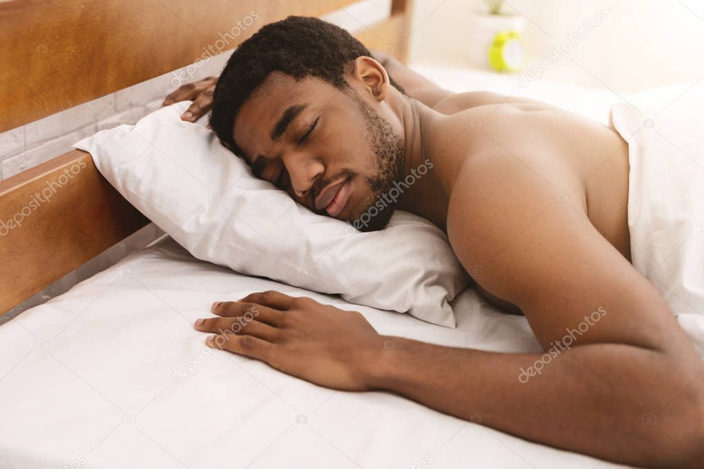 Naked african-american man sleeping in bed closeup