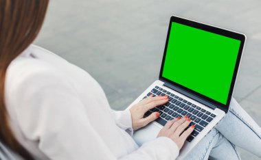 Bin yıllık kadın yeşil ekran ile laptop yazarak