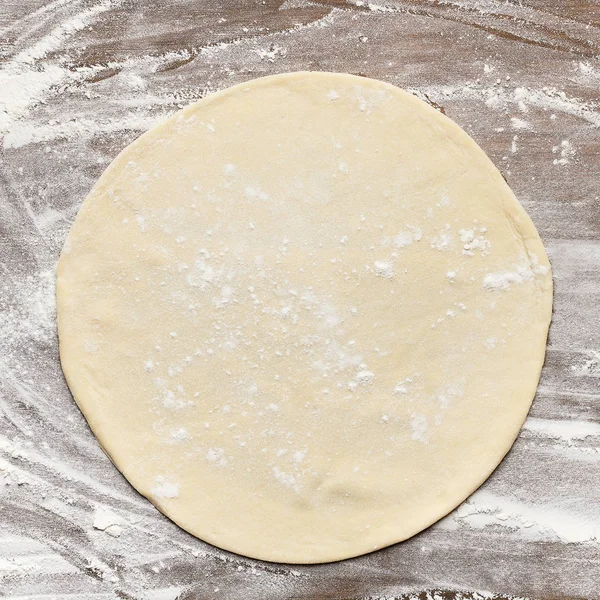 Rolled out pizza dough on floured surface