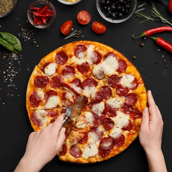 Koch schneidet frisch zubereitete Pizza in Scheiben — Stockfoto