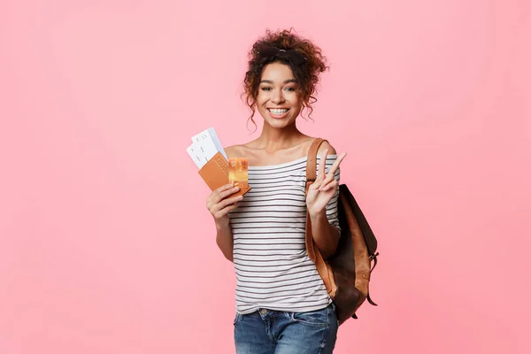 Chica feliz sosteniendo billetes de avión y mostrando gesto de paz — Foto de Stock