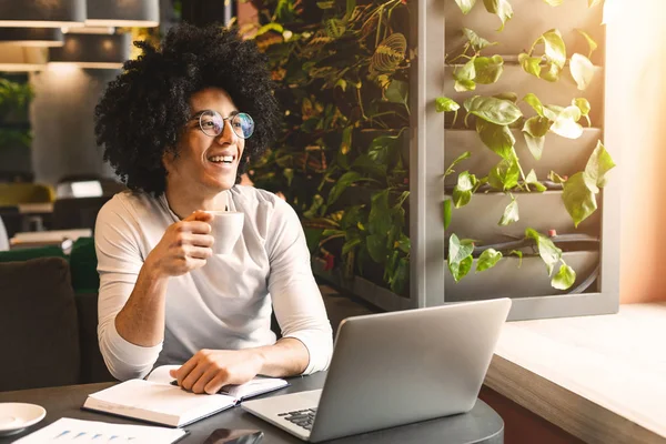 Jovem empresário com café trabalhando no laptop no café — Fotografia de Stock