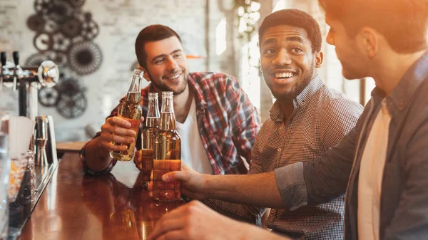 Amigos bebiendo cerveza y charlando en el mostrador en el pub — Foto de Stock