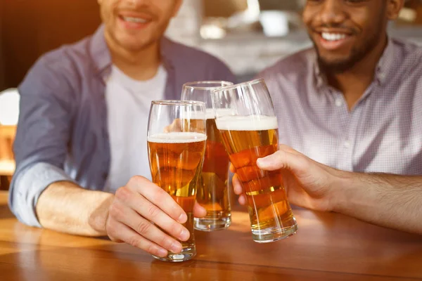 Лучшие друзья звонят в пивные бокалы в баре, крупным планом — стоковое фото