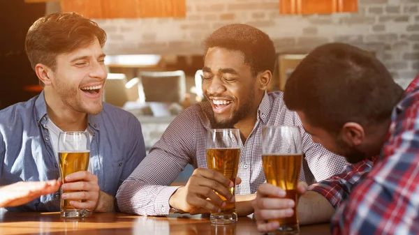 Best friends having fun and drinking beer at bar counter