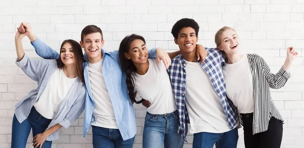 Diversi adolescenti che abbracciano e si divertono oltre il muro bianco — Foto Stock