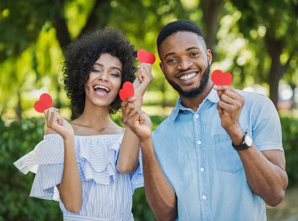 Любящая африканско-американская пара с бумажными сердцами в парке — стоковое фото