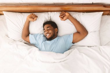 Yatağın üst görünümünde uyuyan genç Afro-Amerikan adam