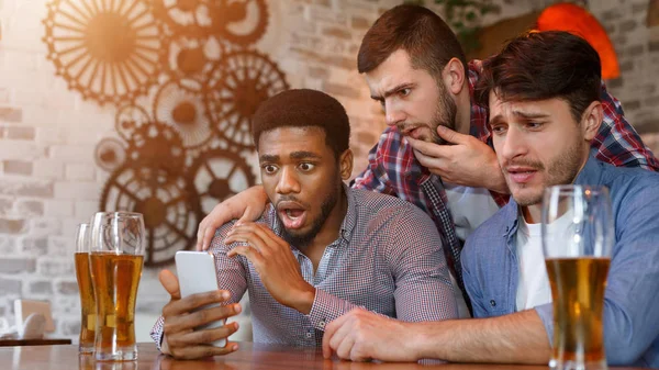 Amigos sorprendidos viendo videos en el teléfono inteligente en el bar — Foto de Stock