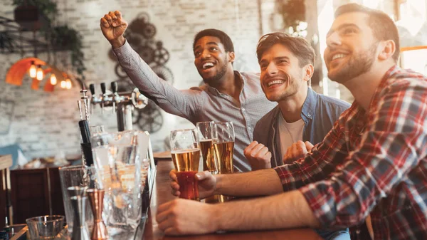 Viendo fútbol en el bar. Felices amigos bebiendo cerveza —  Fotos de Stock