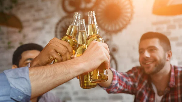Bierflaschen klirren. Freunde ruhen sich gemeinsam in Bar aus — Stockfoto