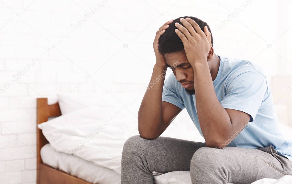 Young sad man touching his head and keeping eyes closed