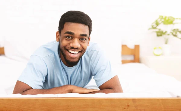 Genç siyah adam yatakta gülümseyen portresi — Stok fotoğraf