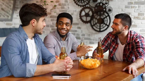 Молодые люди разговаривают, едят чипсы и пьют пиво — стоковое фото