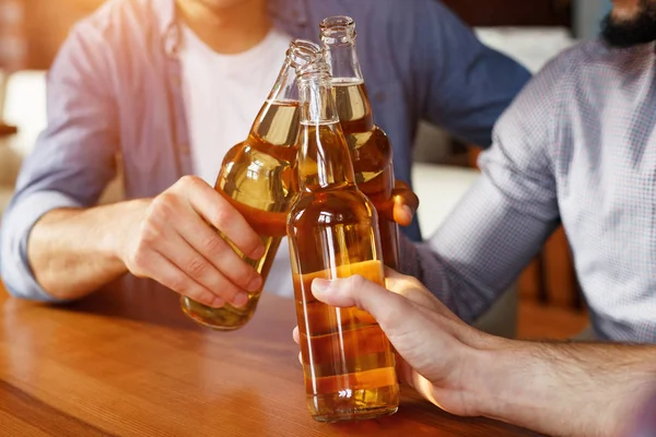 Homens batendo garrafas de cerveja, descansando no bar — Fotografia de Stock