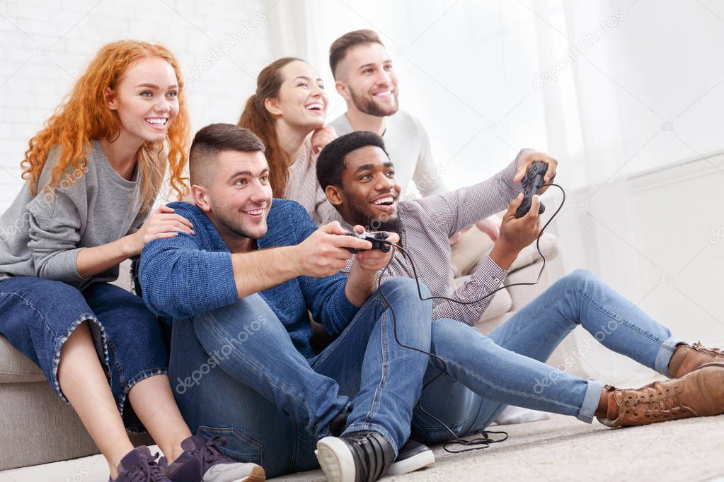 Friends playing video games, having fun at home