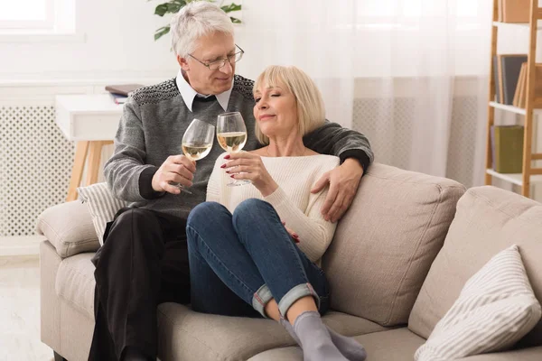 Loving senior couple drinking white wine, celebrating anniversary