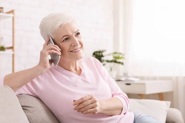 Старшая женщина разговаривает по мобильному телефону дома — стоковое фото
