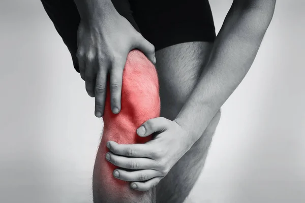 Young man massaging her painful knee closeup — Stock Photo, Image