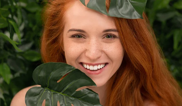 Alegre pelirroja riendo a través de monstera hojas — Foto de Stock