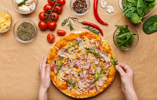 Hausgemachte Pizza. Frau würzt Pizza mit Rucola — Stockfoto