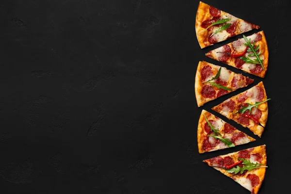 Färsk pepperoni pizza slices i rad på mörk bakgrund — Stockfoto