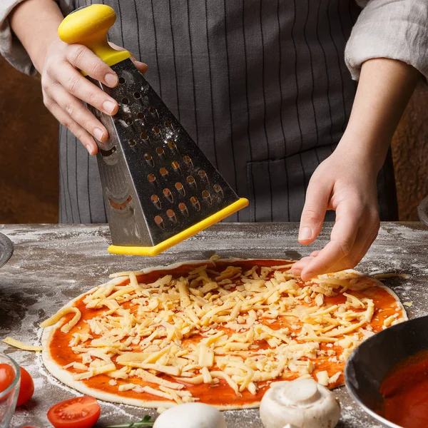 Προετοιμασία πίτσα. Γυναίκα τρίβει τυρί στον τρίφτη — Φωτογραφία Αρχείου