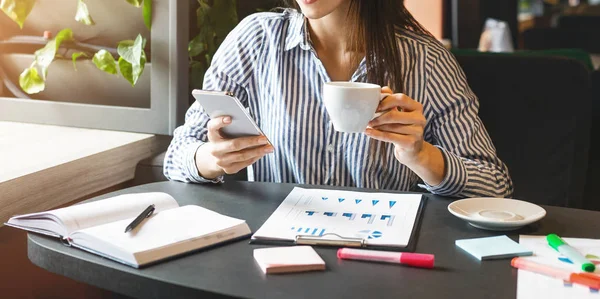 Mujer joven mirando el teléfono inteligente y beber café — Foto de Stock