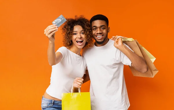 Joven pareja negra con bolsas de compras y tarjeta de crédito — Foto de Stock