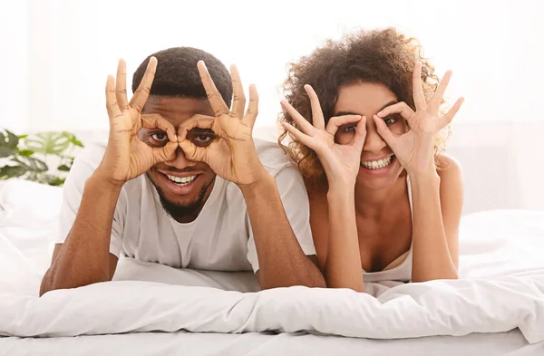 Alegre feliz pareja enamorada sosteniendo los dedos cerca de los ojos — Foto de Stock