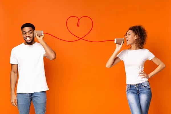 Ung svart par med kan ringa på orange bakgrund — Stockfoto