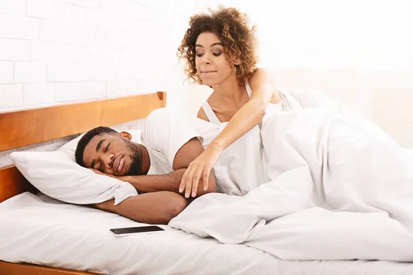 Verdachte vrouw controleren haar slapende man cellphone in bed — Stockfoto
