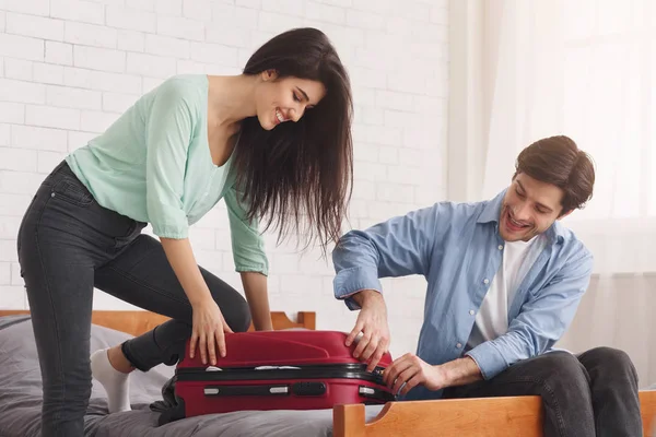 Пара закриває повну валізу, готуючись до відпустки — стокове фото