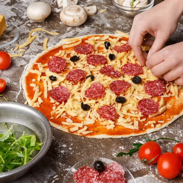 Frau dekoriert Pizza mit verschiedenen Zutaten, Ernte — Stockfoto