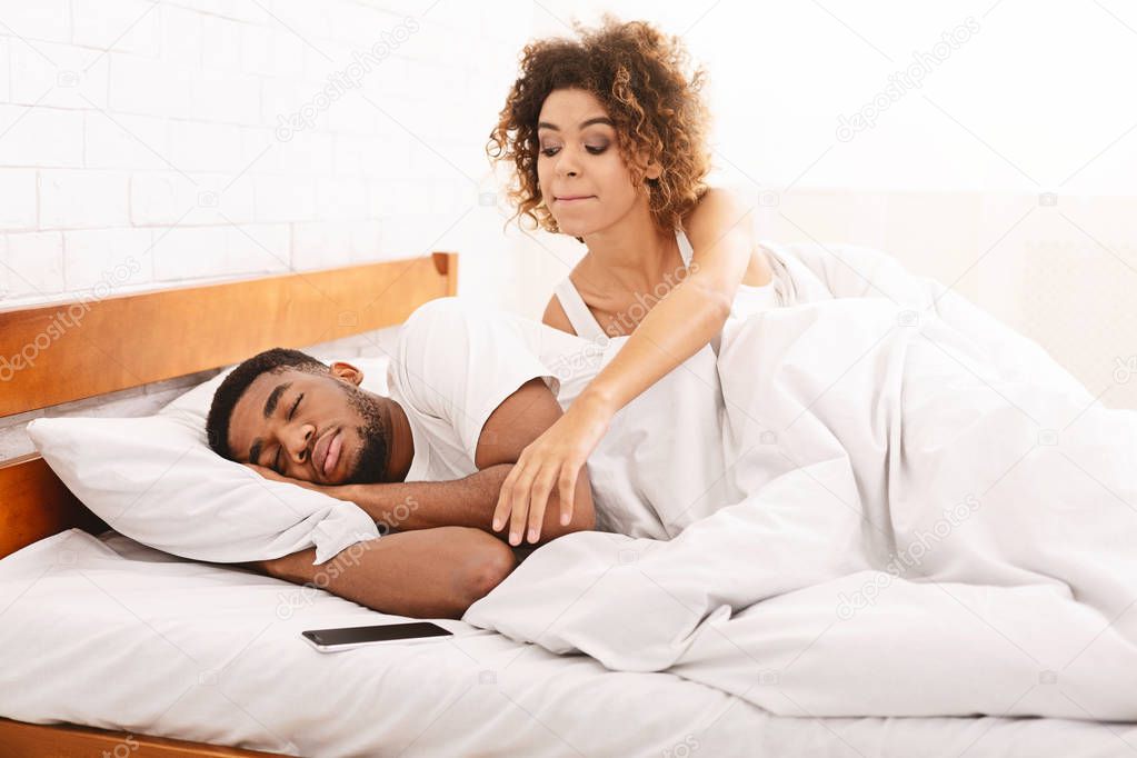 Suspicious wife checking her sleeping husband cellphone in bed