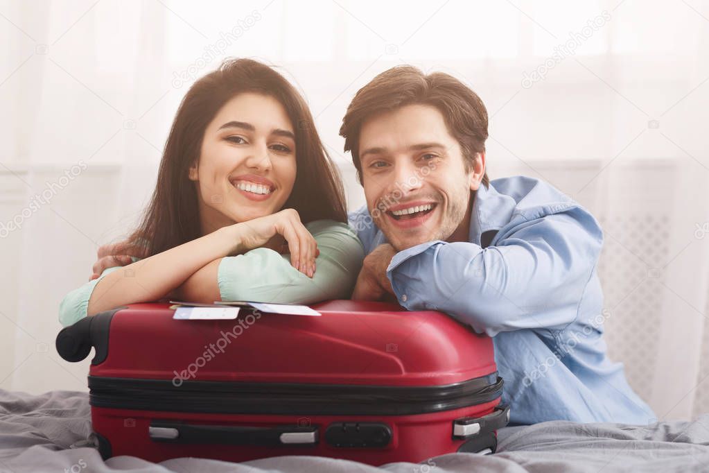 Loving couple leaning on suitcase, preparing for vacation