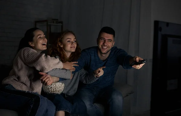 Glückliche Freunde vor dem Fernseher und beim Kanalwechsel — Stockfoto