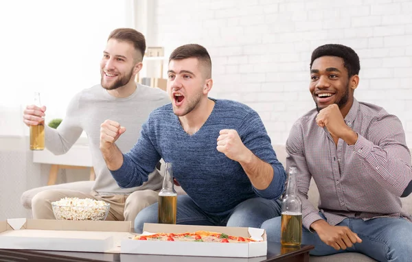 国内のファン。サッカーを見て、ピザを食べる 3 人の男性 — ストック写真