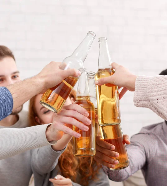 Friends clinking beer bottles, having home party — Stock Photo, Image