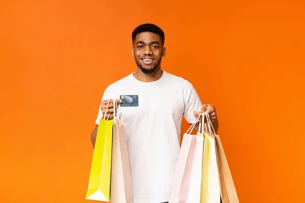 Afrikanisch-amerikanischer Mann mit bunten Papiertüten und Kreditkarte — Stockfoto