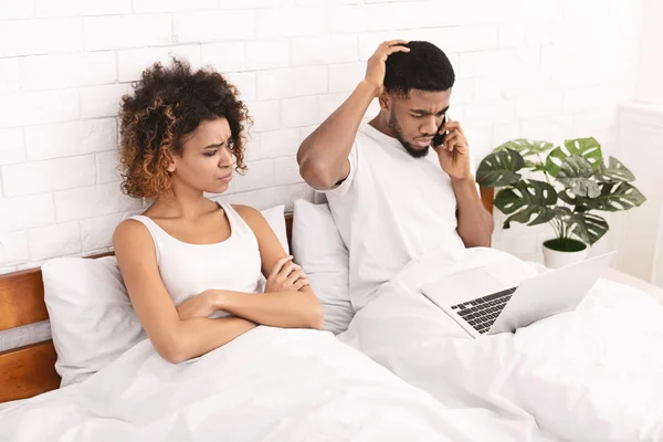 African-american guy working in bed and ignoring his wife