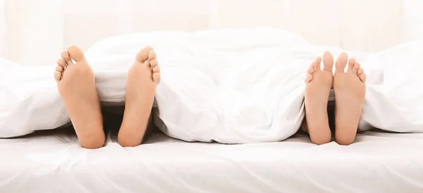 Úpatí Černé pár v posteli pod dekou — Stock fotografie